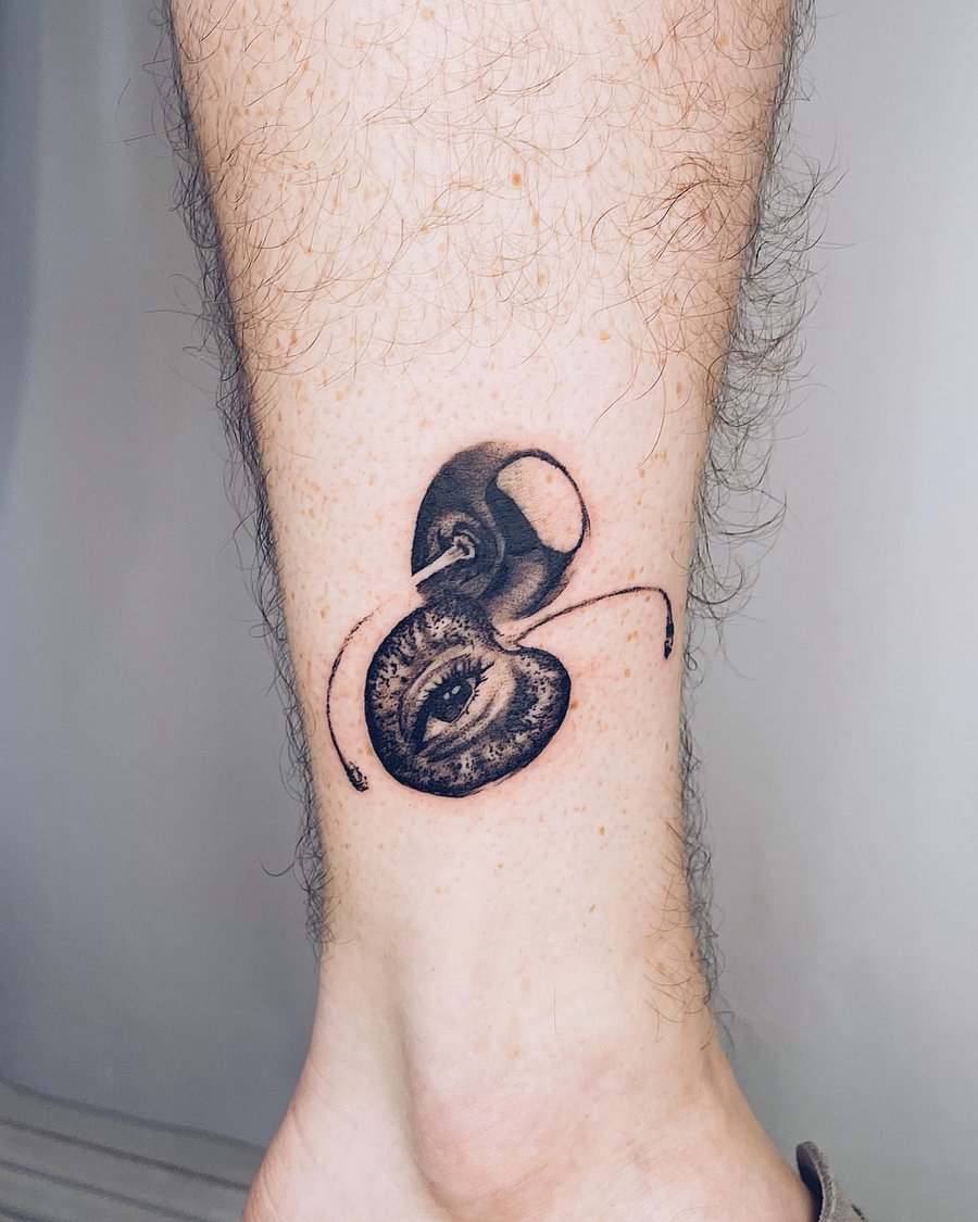 A surreal black and grey tattoo of an eye integrated into an ant design on the calf, featuring bold blackwork style — by Level tattoo, los angeles