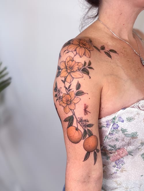 A colorful illustrative tattoo of an orange branch with flowers on the shoulder, featuring delicate and romantic details — by Melanie Benoit, los angeles
