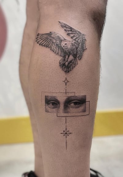 A black and grey illustrative tattoo on the calf featuring a detailed owl in flight above a geometric design with a pair of eyes and a star-like symbol — by Jian Liang, los angeles