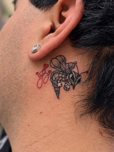 A delicate linework tattoo of a bee with small hearts on the neck, featuring a minimalist style with mixed color profile — by HEAVY INK, los angeles