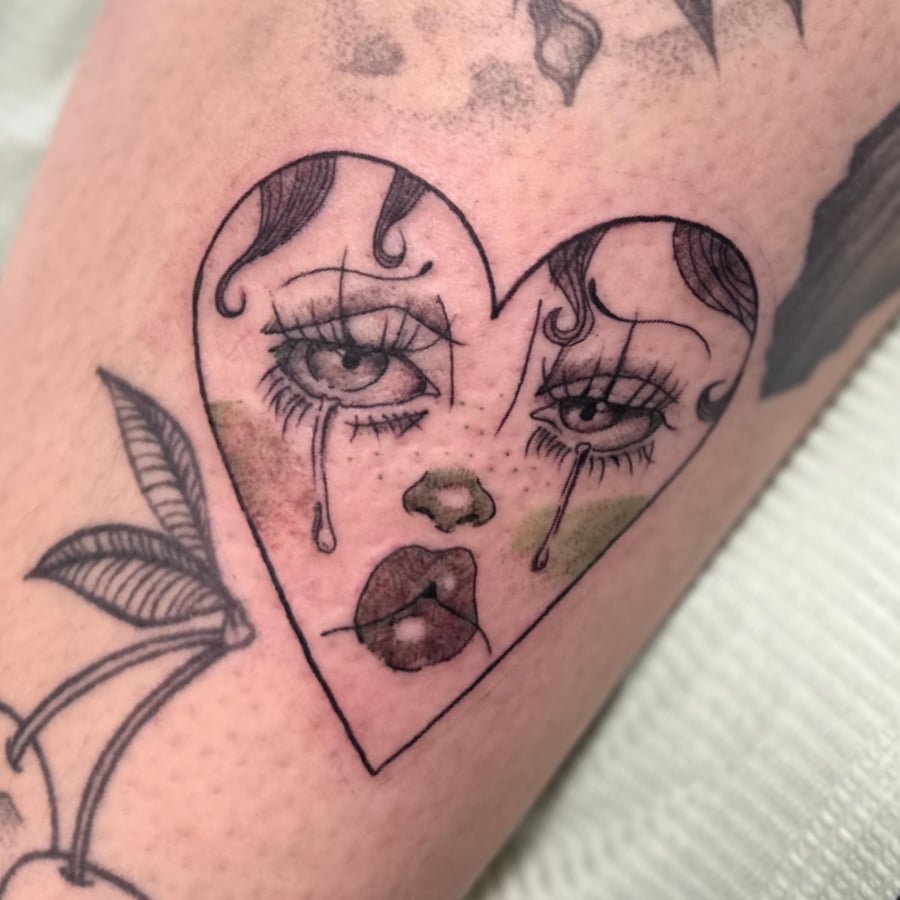 A crying woman's face in a heart shape with green blush, done in blackwork and fine line style — by Maddie Ramirez, los angeles