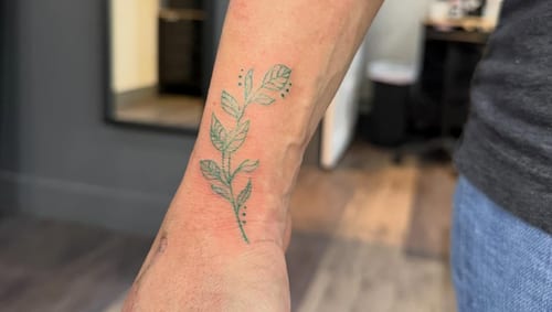 A delicate fine line leaf branch tattoo on the wrist with a minimalist style and green ink — by Kiera Garvin, los angeles