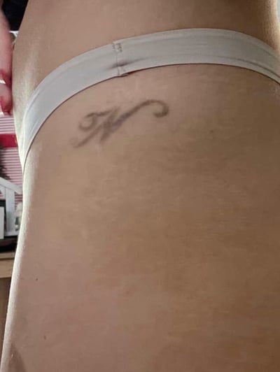 A minimalist black and grey letter 'K' tattoo on the hip with a simple script style — by Melanie Benoit, los angeles