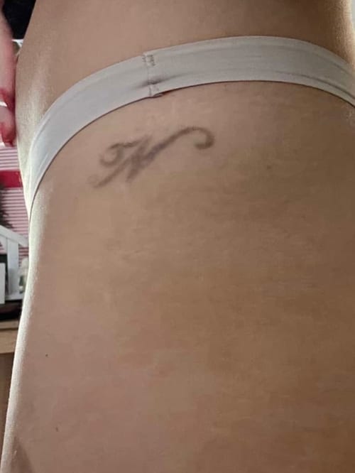 A minimalist black and grey letter 'K' tattoo on the hip with a simple script style — by Melanie Benoit, los angeles