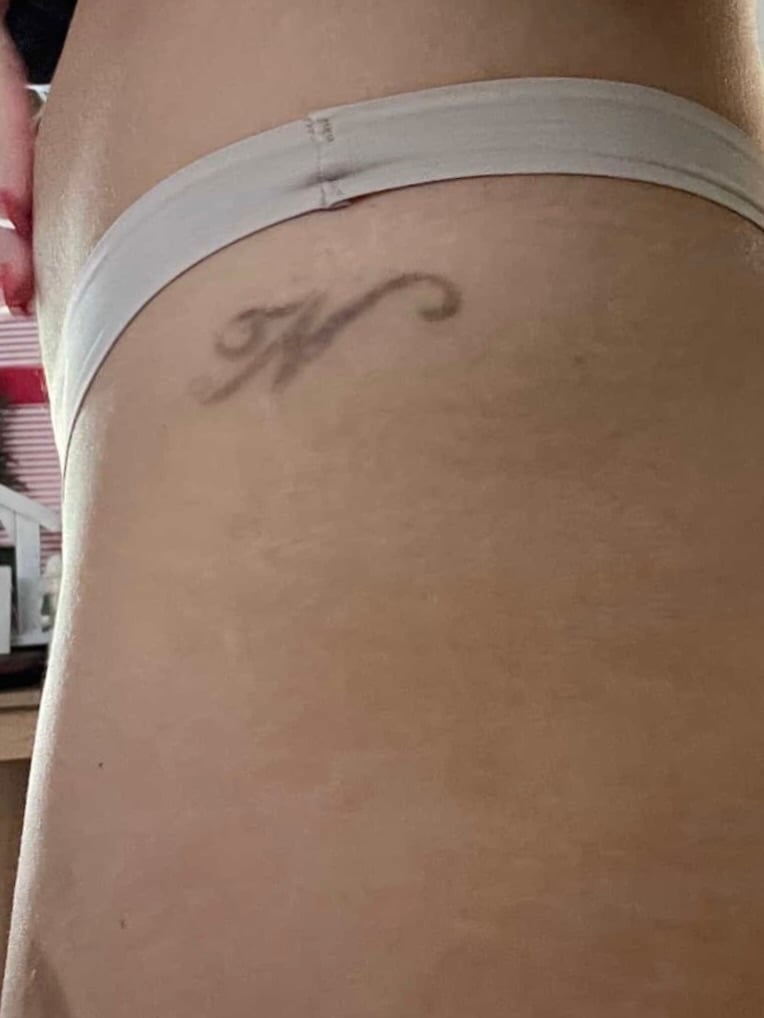 A minimalist black and grey letter 'K' tattoo on the hip with a simple script style — by Melanie Benoit, los angeles