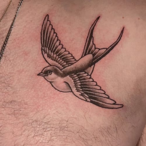 A clean black and grey tattoo of a flying bird on the chest, done in a traditional style — by Miguel ANGELO, los angeles