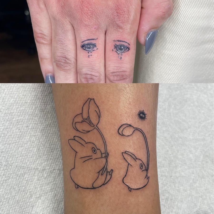 A delicate fine line tattoo featuring eyes on fingers and whimsical rabbits with flowers on the hand — by Sandra Price, los angeles