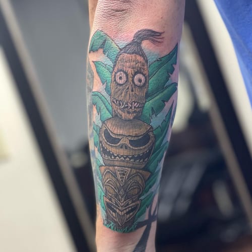 A colorful tiki totem tattoo on the forearm with bold and graphic Polynesian influences — by Sandra Price, los angeles