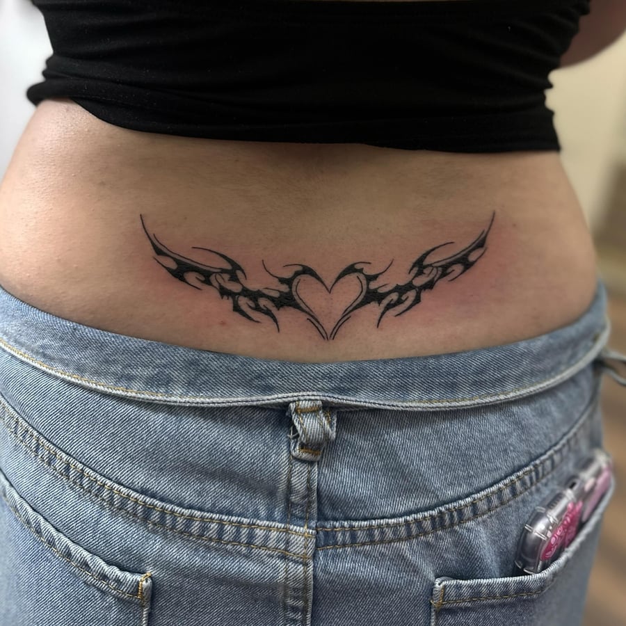 A bold blackwork tribal heart design tattoo on the lower back — by Maddie Ramirez, los angeles