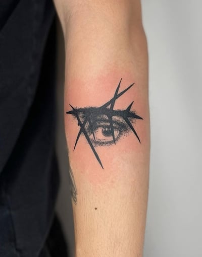 A black and grey abstract tattoo of an eye with sharp geometric elements on the arm — by Level tattoo, los angeles