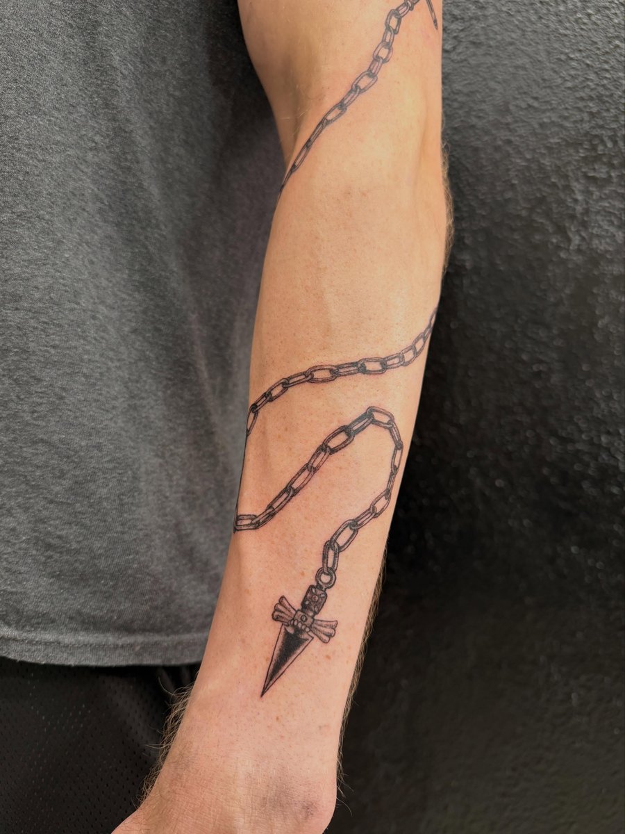 A bold blackwork tattoo of a chain with a dagger pendant on the forearm, featuring detailed linework — by Kiera Garvin, los angeles