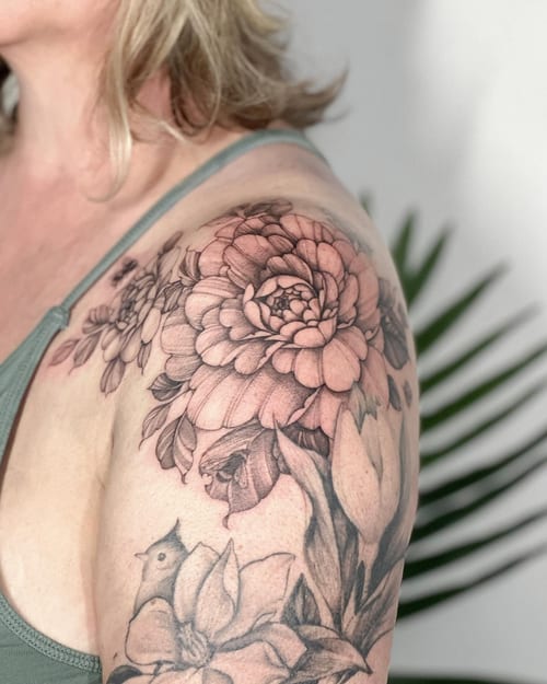 A delicate black and grey floral bouquet tattoo on the shoulder with intricate petal details — by Melanie Benoit, los angeles