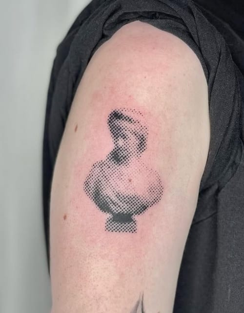 A black and grey dotwork tattoo of a bust on the upper arm, featuring intricate dot shading to create a portrait effect — by Level tattoo, los angeles