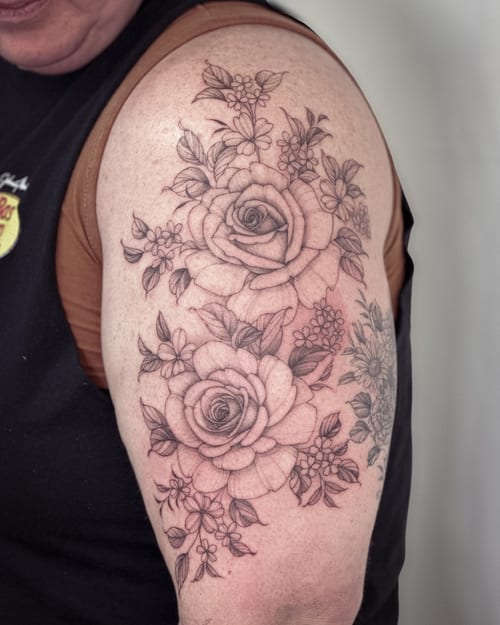 A delicate black and grey rose bouquet tattoo on the upper arm with detailed floral elements — by Melanie Benoit, los angeles