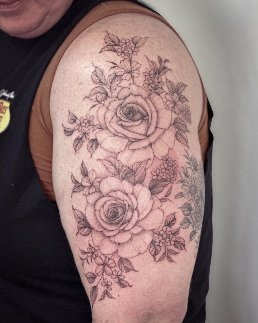 A delicate black and grey rose bouquet tattoo on the upper arm with detailed floral elements — by Melanie Benoit, los angeles