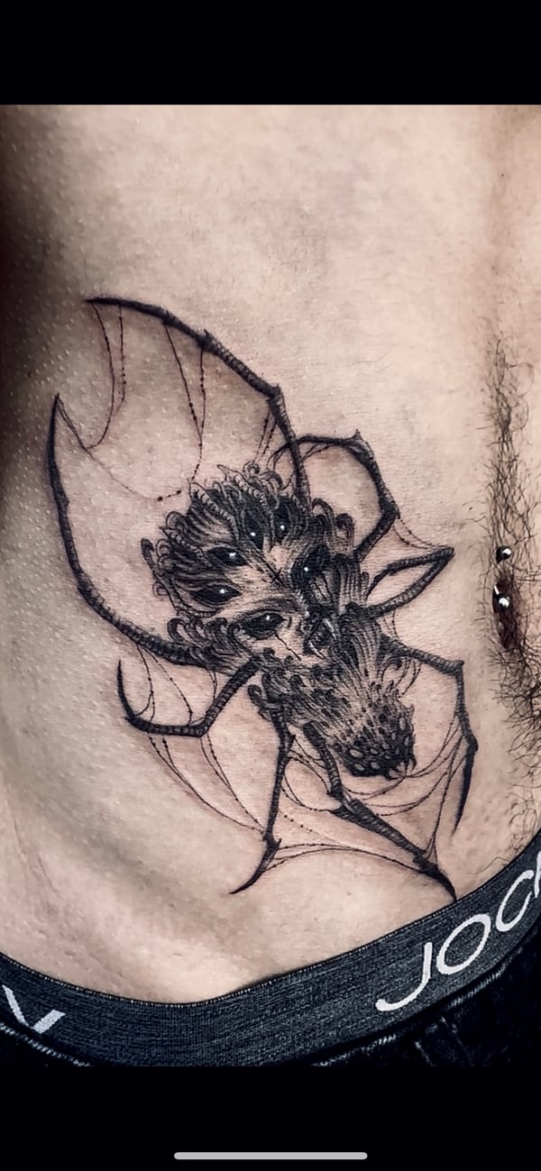 A detailed black and grey linework tattoo of a spider on the rib, featuring intricate patterns and shading — by zitronxus, los angeles