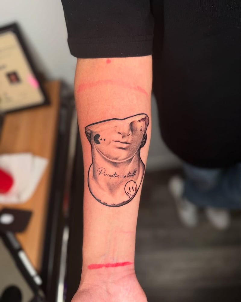 surrealist black and grey tattoo of a classical marble bust with a dissolving face and the words perception is truth by zealous, a surrealism tattoo artist in the arts district los angeles