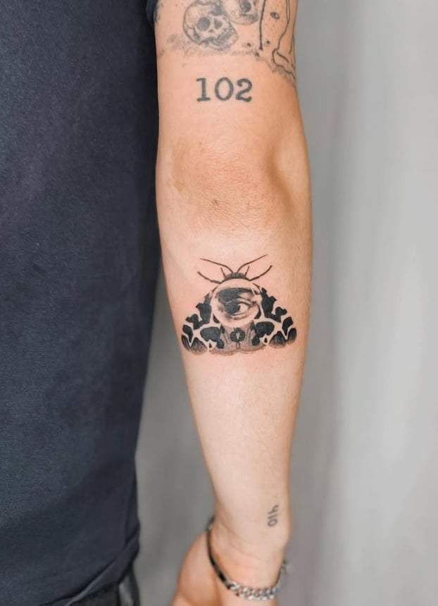A minimalist blackwork tattoo on the forearm featuring an eye above a stylized landscape with trees and mountains — by Level tattoo, los angeles