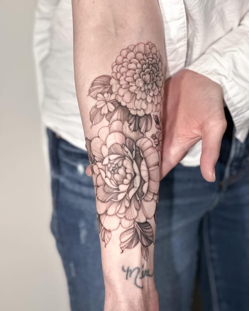 A delicate black and grey floral tattoo on the forearm featuring detailed flowers and leaves — by Melanie Benoit, los angeles