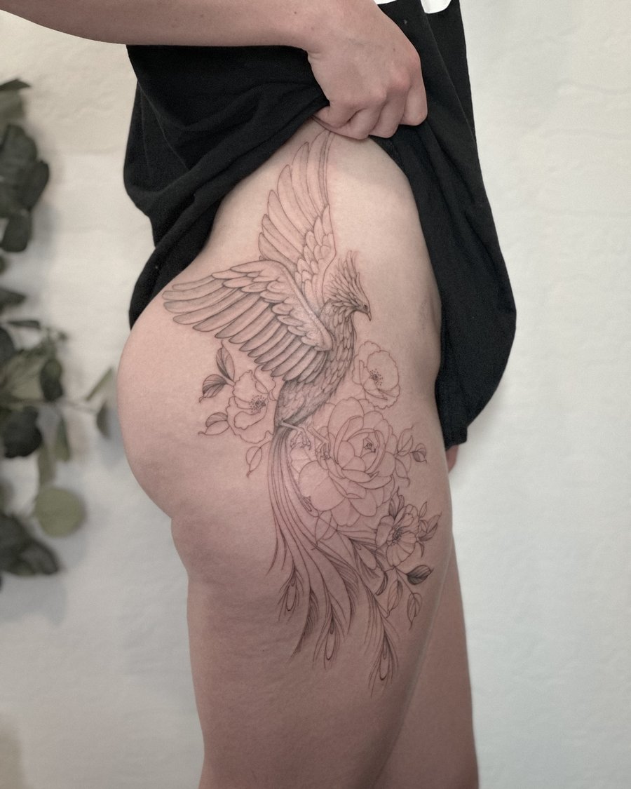 A delicate black and grey fine line tattoo of a phoenix with flowers on the thigh, featuring ornate details and elegant linework — by Melanie Benoit, los angeles