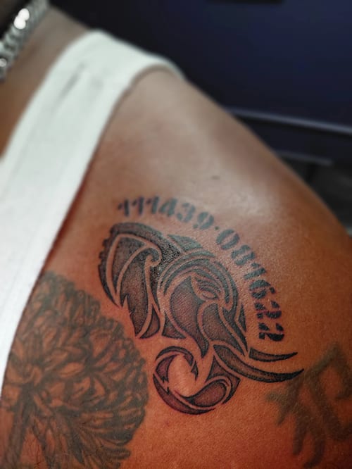 tribal blackwork elephant head with shaded curves and arched numerals above, on the shoulder — by anoetic.designs.ultd, los angeles