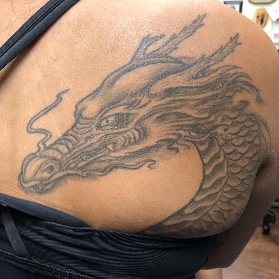A bold black and grey dragon head tattoo on the shoulder, featuring intricate Japanese style details — by Sandra Price, los angeles