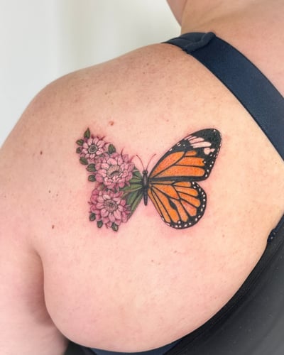 A colorful butterfly with pink flowers tattooed on the back, featuring a realistic style with delicate details — by Melanie Benoit, los angeles