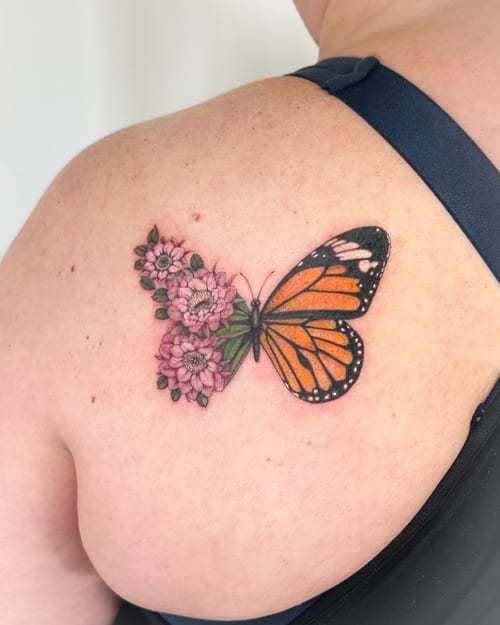 A colorful butterfly with pink flowers tattooed on the back, featuring a realistic style with delicate details — by Melanie Benoit, los angeles
