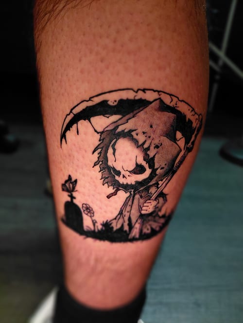 A black and grey illustrative tattoo of a cartoonish grim reaper with a scythe on the calf, featuring bold outlines and dark shading — by anoetic.designs.ultd, los angeles