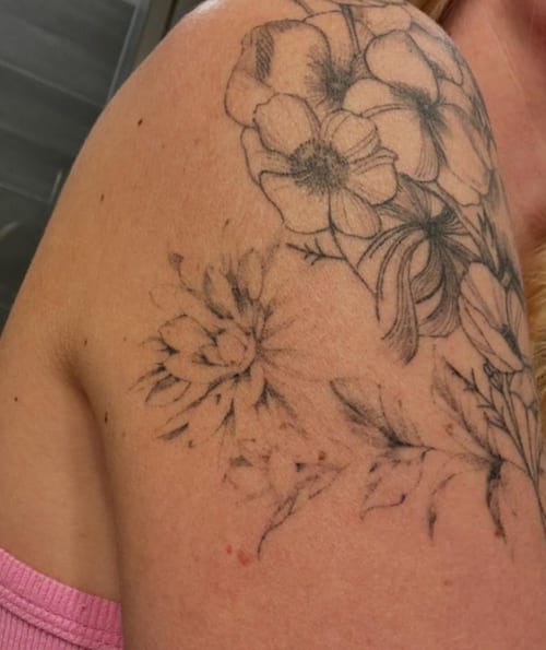 A delicate black and grey floral arrangement tattoo on the shoulder, featuring fine line work and intricate details — by Melanie Benoit, los angeles