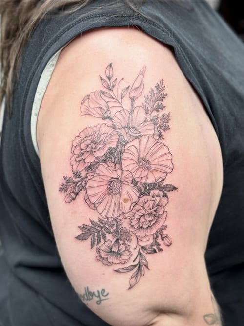 A delicate black and grey floral bouquet tattoo on the upper arm, featuring fine line work and intricate details — by Sandra Price, los angeles