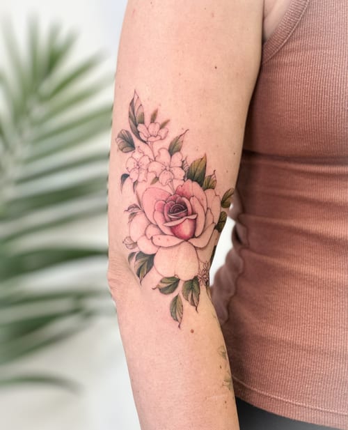 A delicate color rose bouquet tattoo on the upper arm with fine line detailing and soft shading — by Melanie Benoit, los angeles
