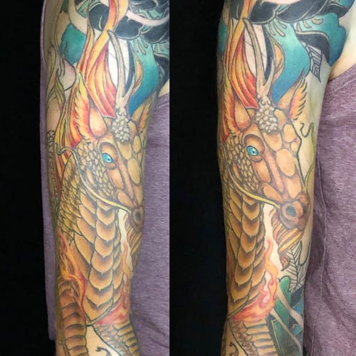 A colorful Japanese dragon tattoo covering the full sleeve with bold and ornate details — by Sandra Price, los angeles