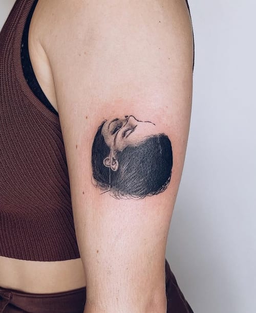 A black and grey realism portrait of a woman's face on the upper arm, featuring fine detail and soft shading — by Level tattoo, los angeles