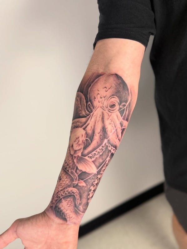 A detailed black and grey tattoo of an octopus and koi fish on the forearm, showcasing realistic textures and shading — by zealous, los angeles