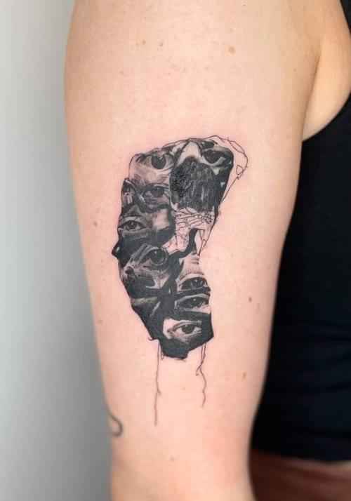 A surreal black and grey tattoo on the upper arm featuring multiple eyes and faces intertwined in an abstract design — by Level tattoo, los angeles