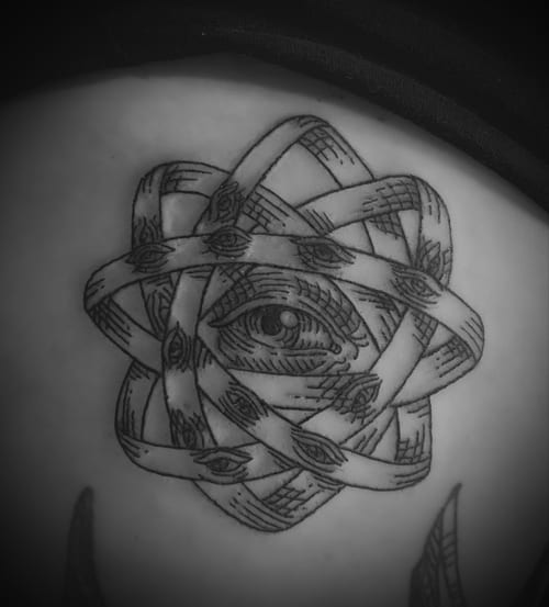 A surreal black and grey tattoo on the back featuring an eye surrounded by interwoven ribbons adorned with smaller eyes — by Tag Devilish, los angeles