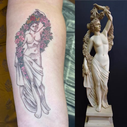 A delicate tattoo of a woman surrounded by flowers on the arm, inspired by a statue, in black and grey with color accents — by Sandra Price, los angeles