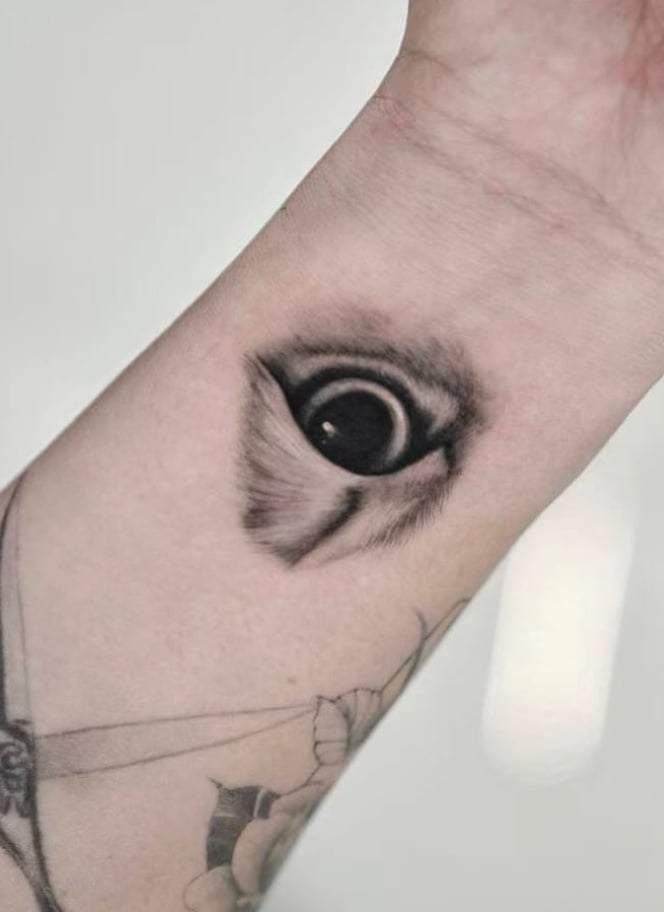 A realistic black and grey depiction of an eye on the wrist with detailed shading and texture — by otaybeatdown, los angeles