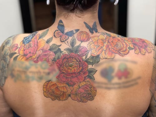 A colorful floral bouquet with butterflies on the back, done in a neo-traditional style with ornate details — by Sandra Price, los angeles