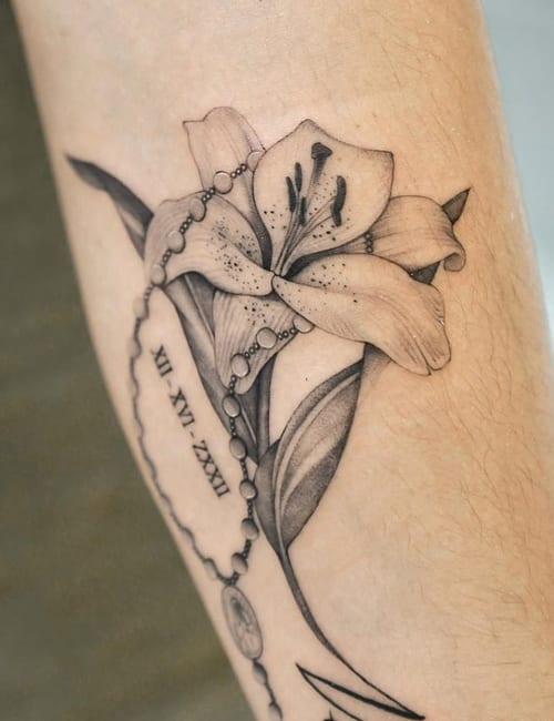 A fine line black and grey tattoo of a lily flower with a rosary and Roman numerals on the forearm, featuring delicate shading and intricate details — by otaybeatdown, los angeles