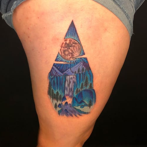A colorful illustrative tattoo of a mountain landscape with a moon and waterfall on the thigh — by Sandra Price, los angeles