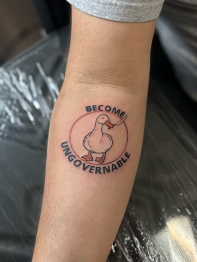 A whimsical fine line tattoo of a goose holding a knife with script lettering on the forearm — by Maddie Ramirez, los angeles