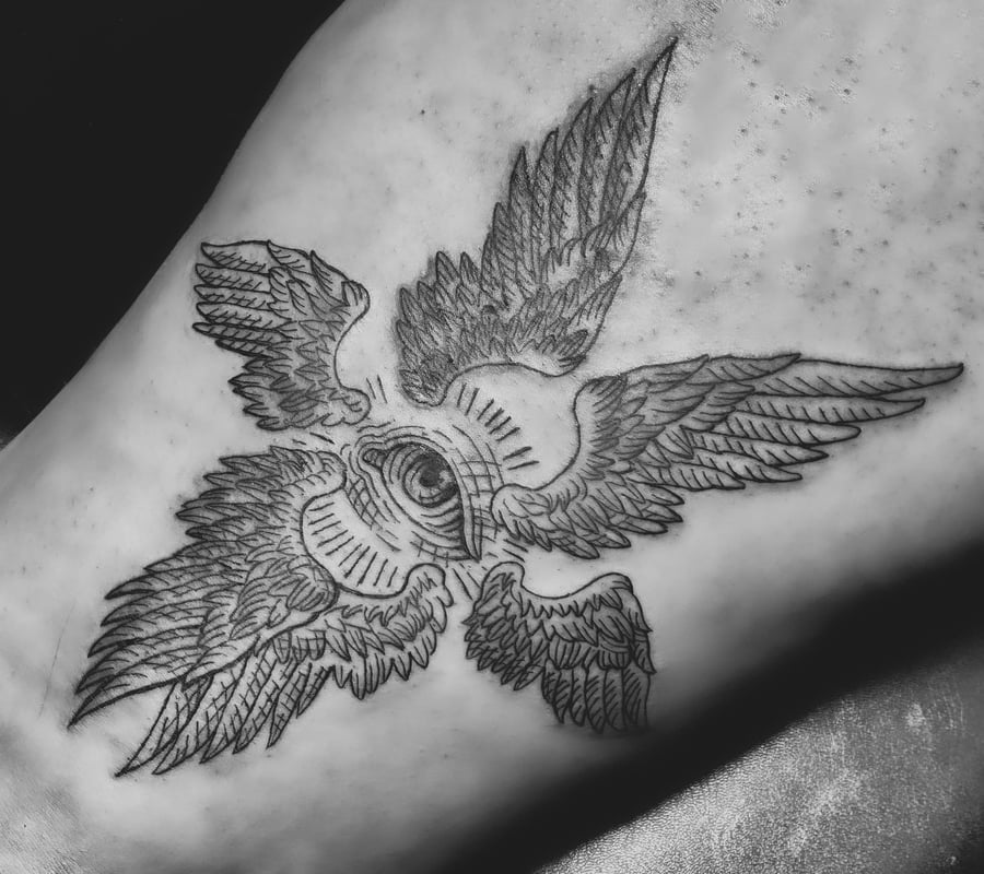 A black and grey linework tattoo on the rib depicting an eye surrounded by four wings, creating a symmetrical design — by Tag Devilish, los angeles