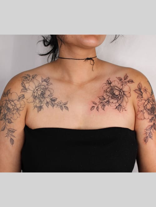 A delicate black and grey floral arrangement tattoo on the shoulders and chest, featuring fine line work and intricate details — by Melanie Benoit, los angeles