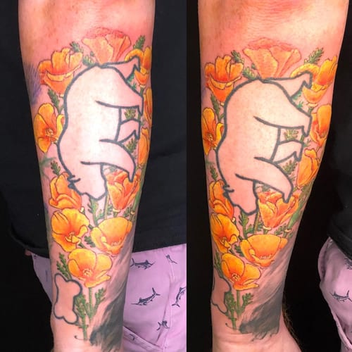 A whimsical illustrative tattoo of a bear surrounded by colorful flowers on the forearm — by Sandra Price, los angeles