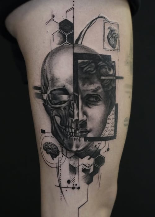 A black and grey surrealistic tattoo on the thigh, combining a skull and a classical face with geometric elements and intricate linework — by Jian Liang, los angeles
