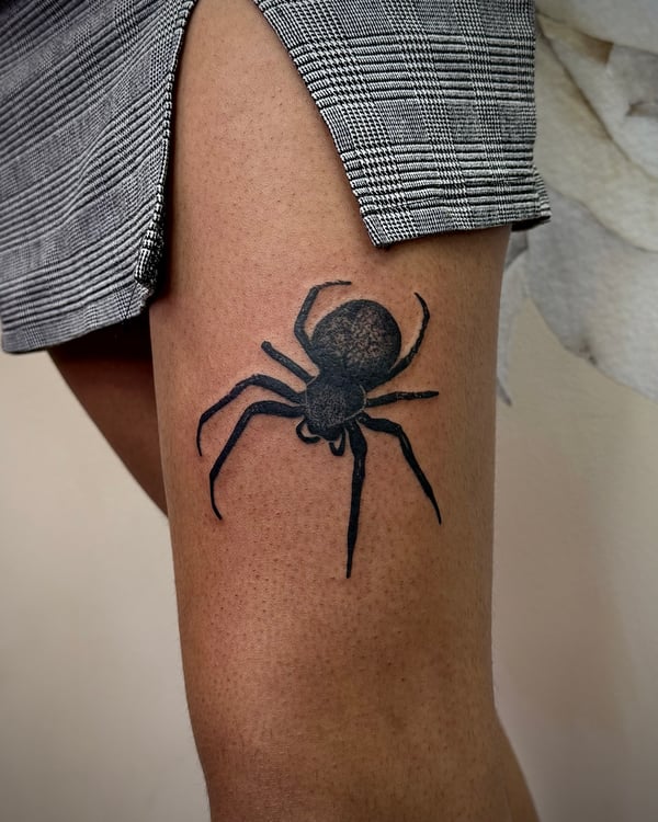 A realistic black and grey spider tattoo on the thigh, featuring detailed linework and shading — by emily, rahway