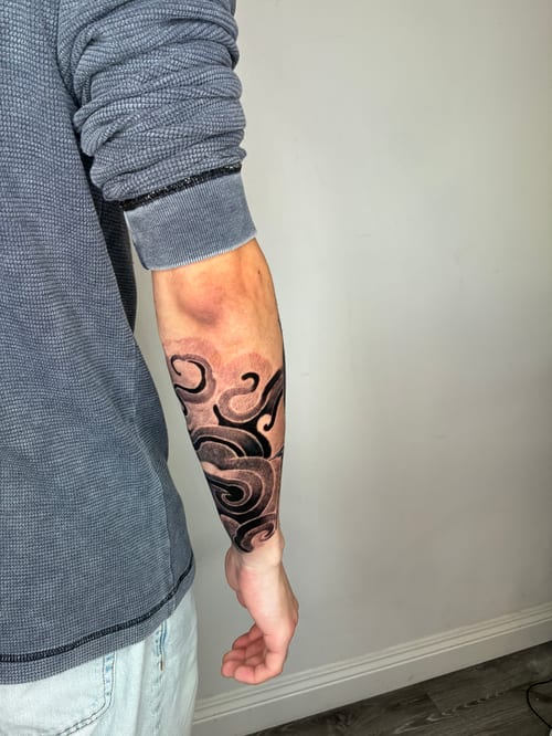An abstract black and grey tattoo with swirling patterns covering the forearm — by Edgar Armas Rodriguez, los angeles