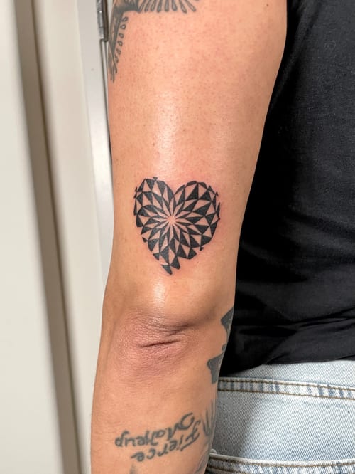 A bold black and grey geometric heart tattoo on the arm, featuring intricate sacred geometry patterns — by Brian Kies, los angeles
